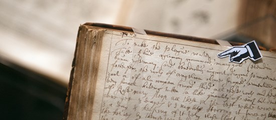 An old manuscript book with a photocopy or a finger pointing at a section of the page.